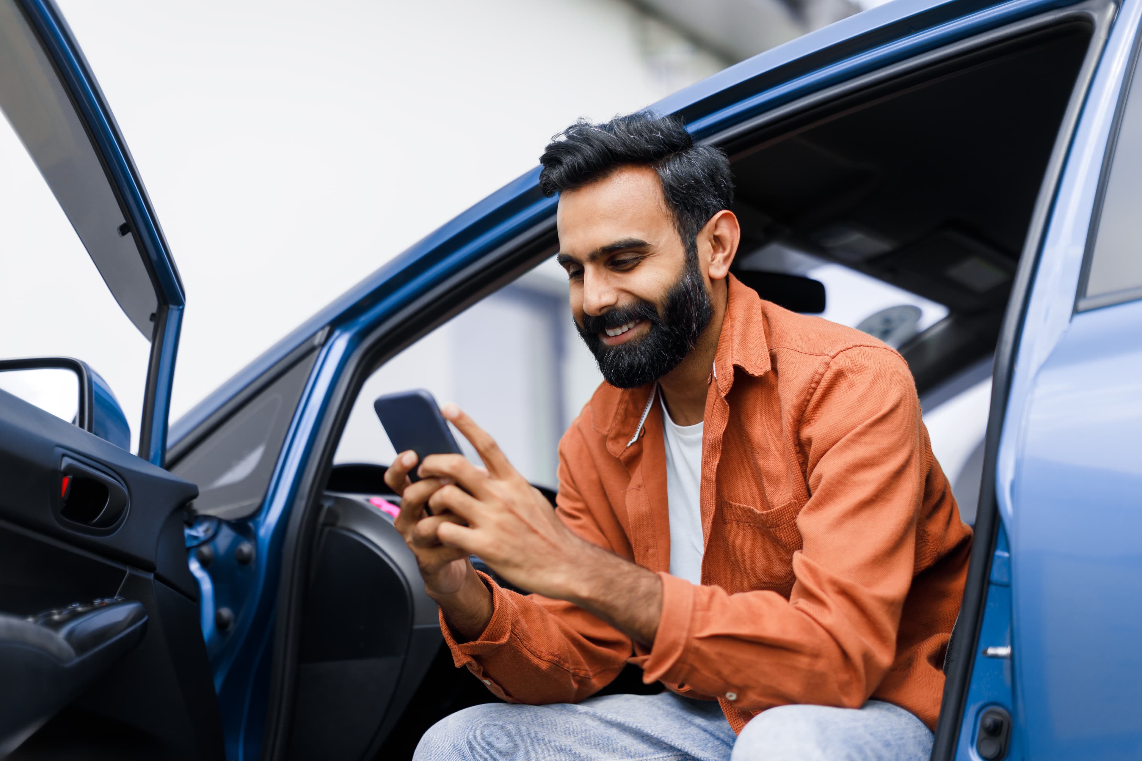 Homem feliz usando celular no carro